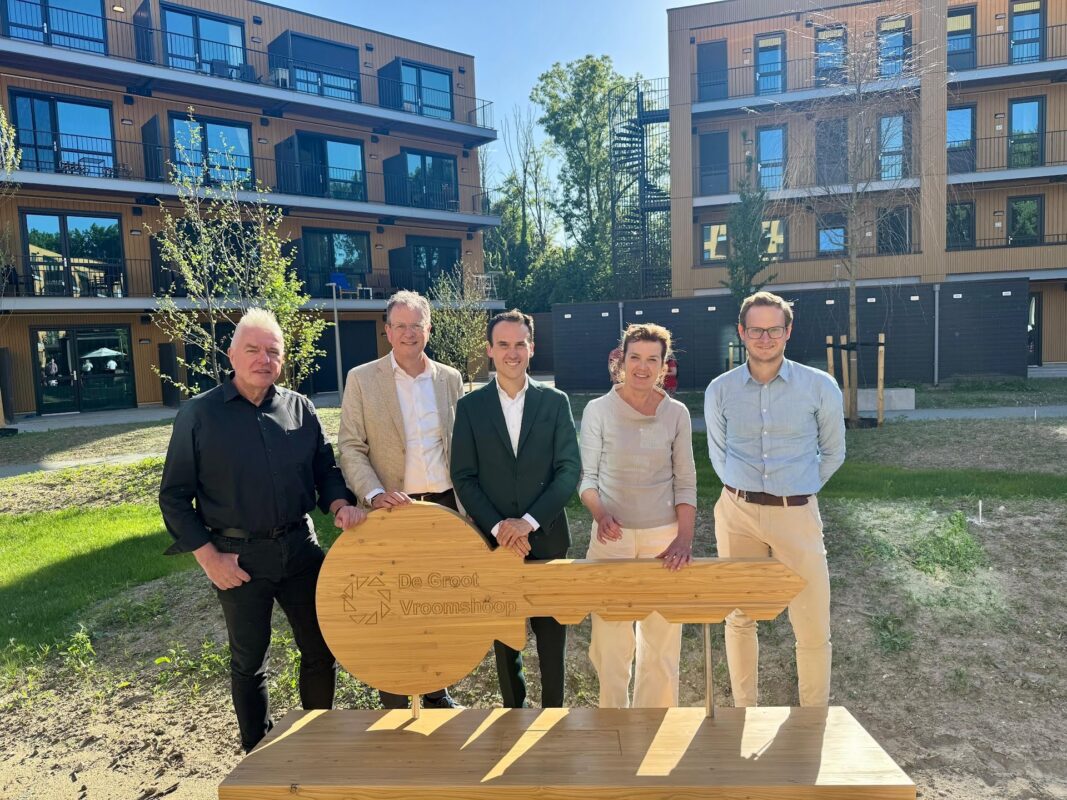 Wethouder Wonen, Paul Smeulders, staat samen met medewerkers van bouwbedrijf De Groot Vroomshoop bij de officiële opening van het woonproject MerWIJde in de wijk Presikhaaf.