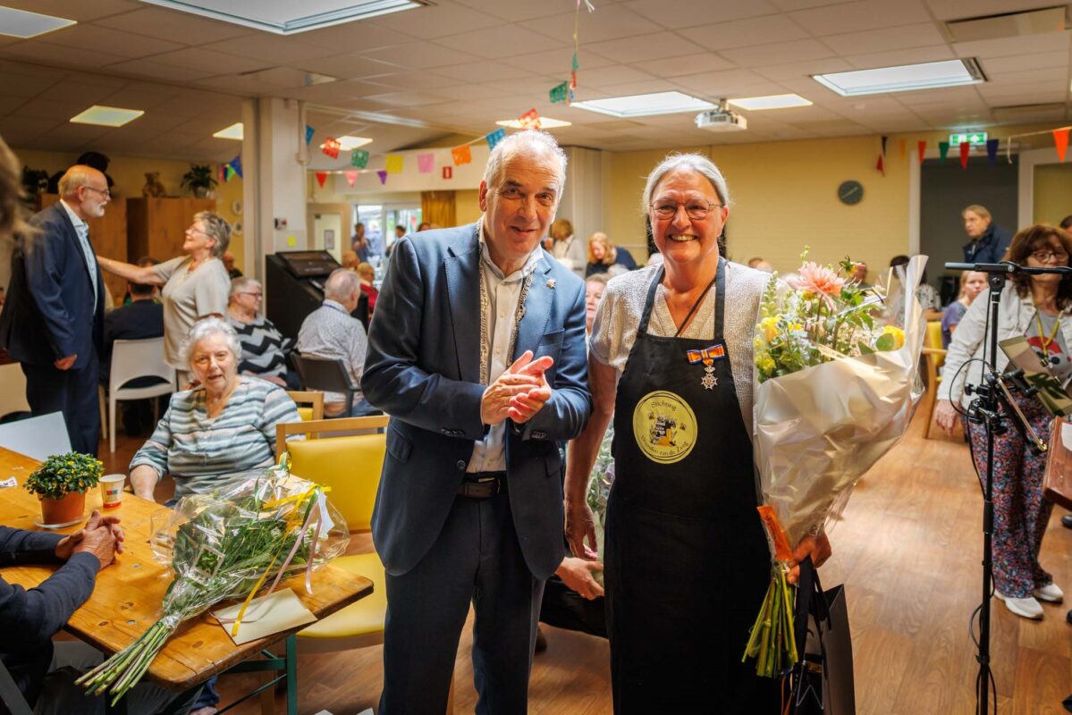 Mevrouw Riek Bouma krijgt een koninklijke onderscheiding uit handen van locoburgemeester Bob Roelofs.