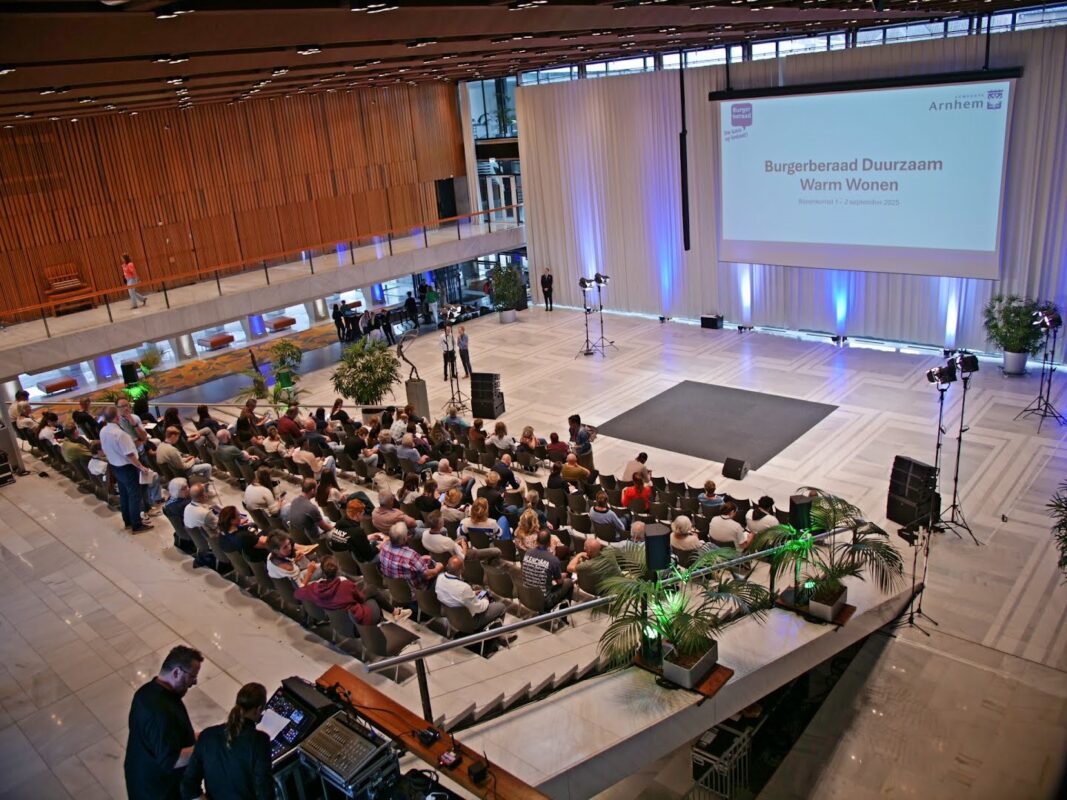 Mensen kijken in de Burgerzaal van het stadhuis naar een presentatie tijdens de aftrap van het burgerberaad.