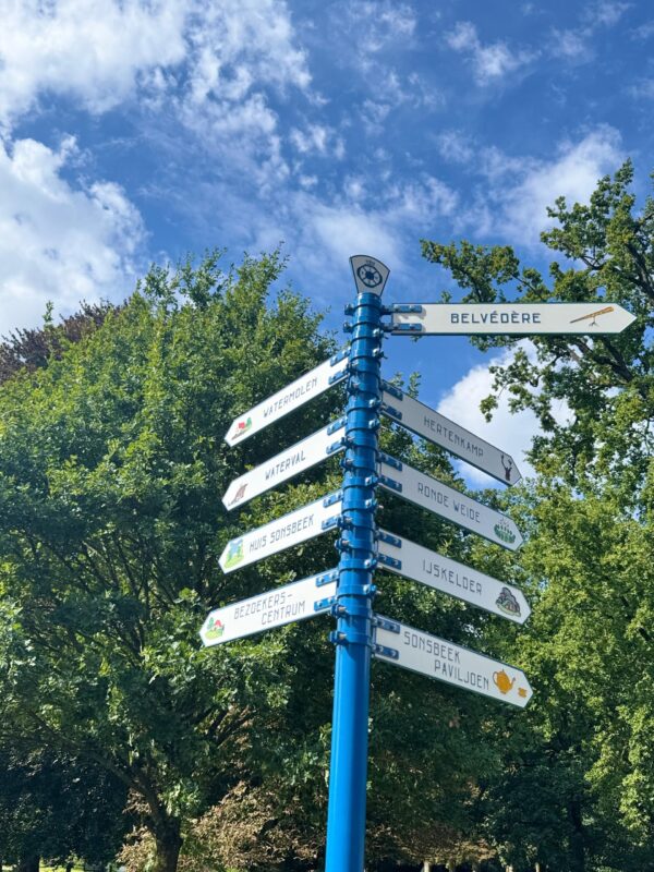 Gerestaureerde wegwijzer bij de hoofdingang van Park Sonsbeek waarop de richting naar de verschillende plekken in het park wordt aangegeven, zoals Belvedere, Hertenkamp, Ronde Weide, IJskelder, Sonsbeek paviljoen, Watermolen, Waterval, Huis Sonsbeek, en Bezoekerscentrum.