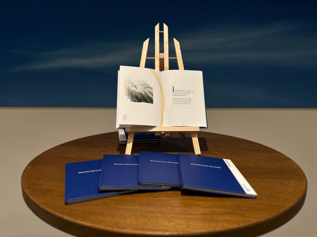 Ronde houten tafel waarop 4 gedichtenbundels liggen en op een standaard is een gedichtenbundel opengeslagen.